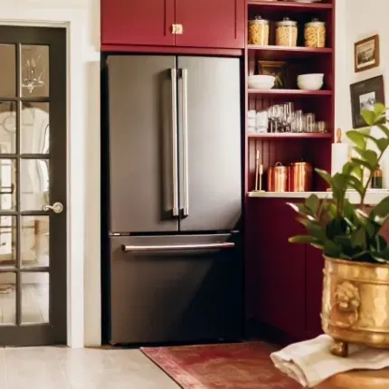 stainless steel fridge in small kitchen corner with red cabinets